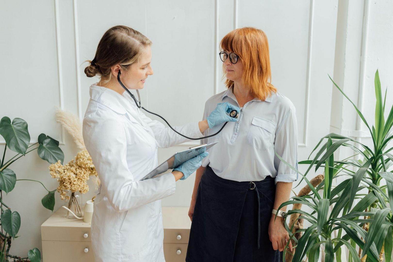 Vårdpersonal lyssnar på patientens hjärta i ett ljust rum